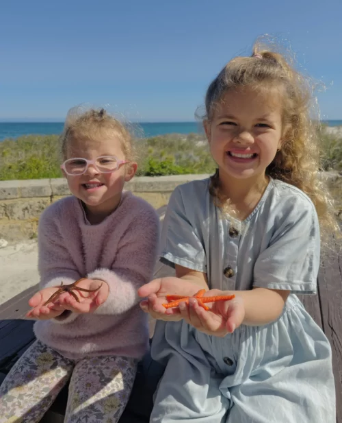 Two children are holding starfish in their outstretched hands