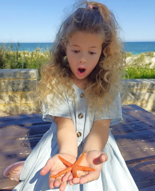 a young girl holding a red star fish