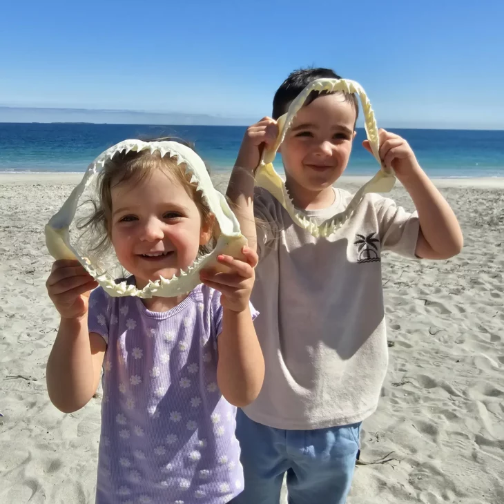 two young children holding shark jaws up to their faces