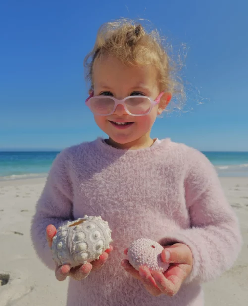 a young girl holding sea urchins at the beach