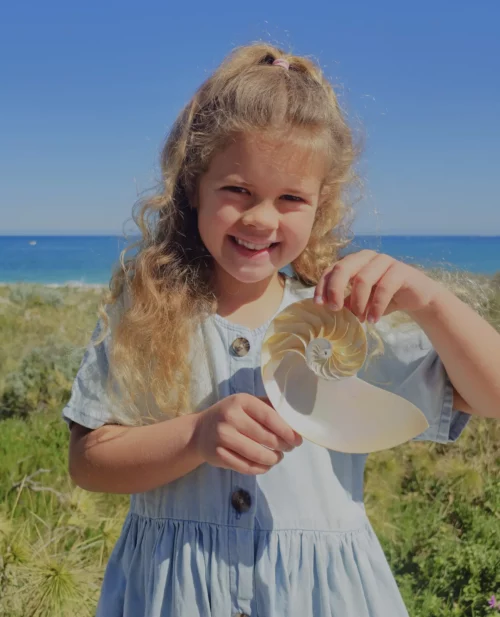 a young girl holding an intricate shell