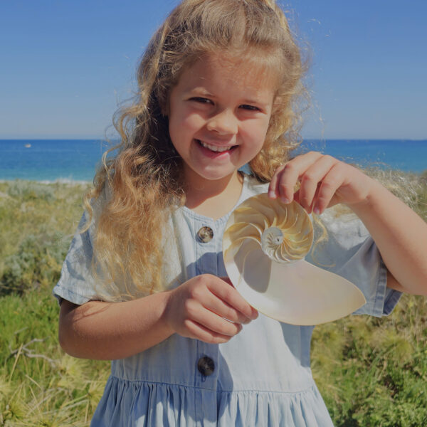 a young girl holding an intricate shell